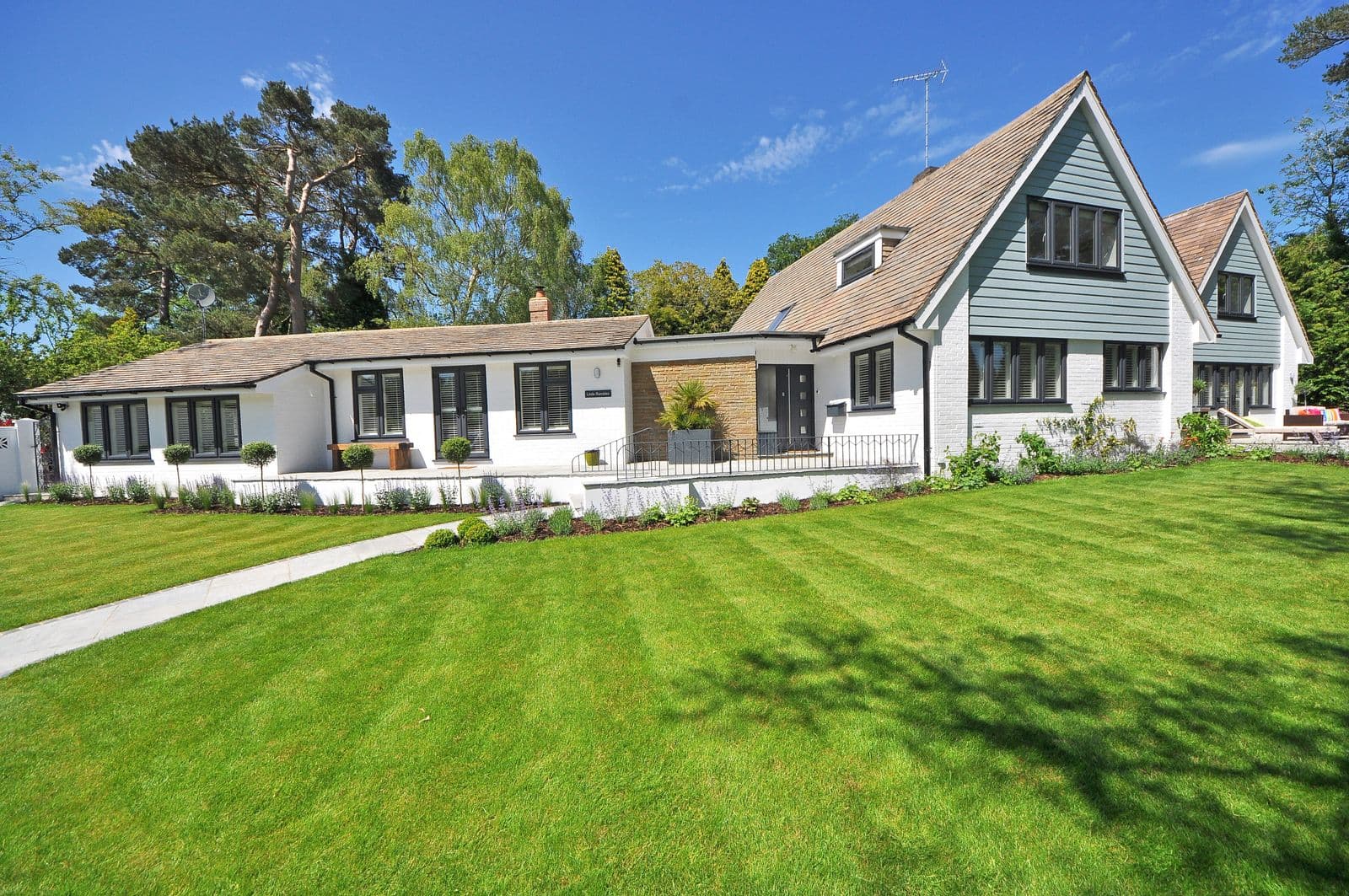 A tidy white house with a large lawn on a bright day